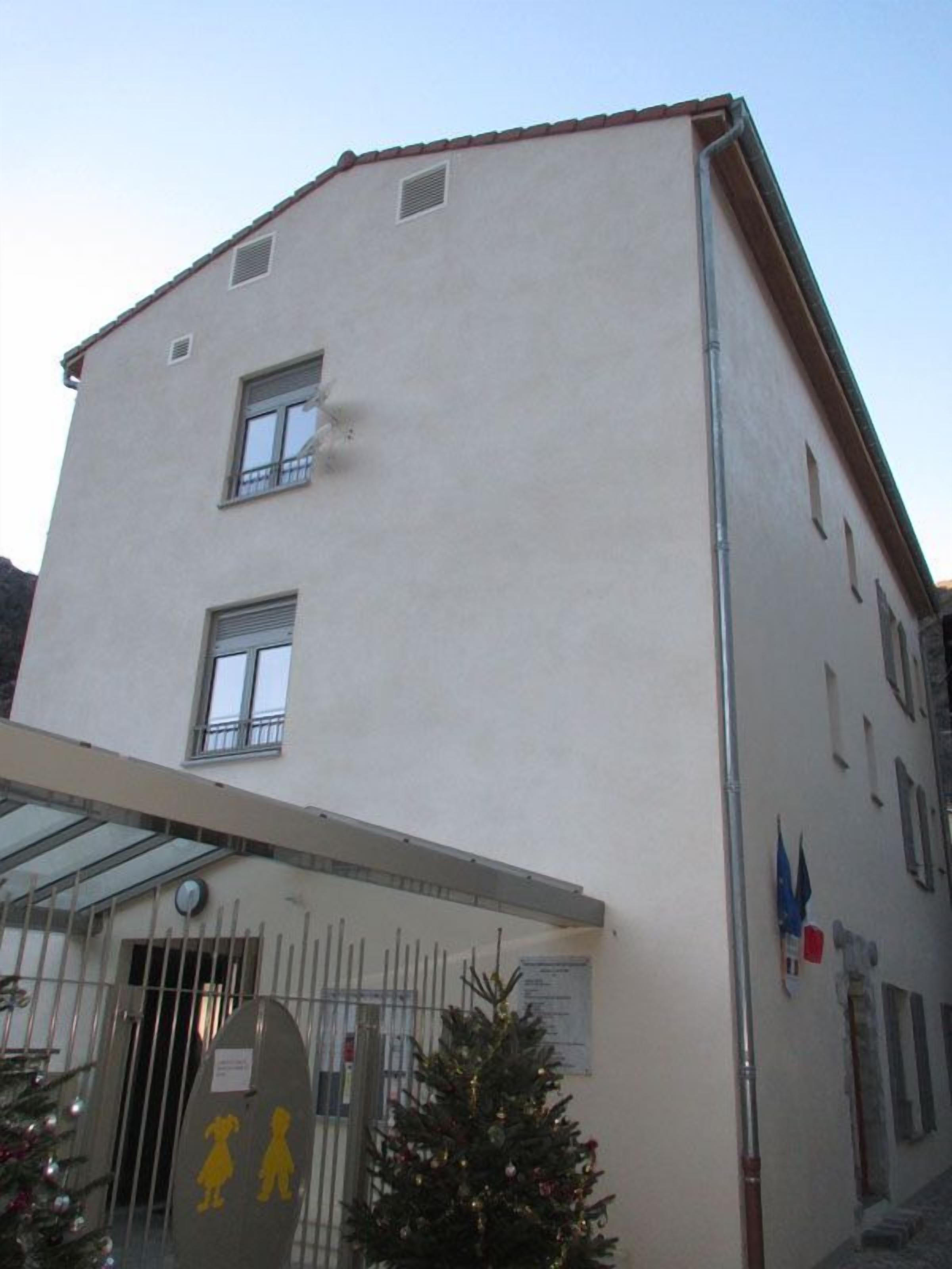 A building with a flat facade, two visible windows, and a covered entrance area.