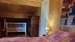 A bedroom with a wooden ceiling, a bunk bed, a door, and a wall painting.