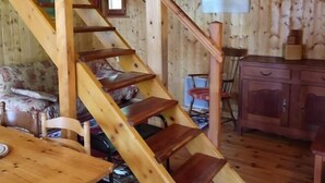A wooden interior with a staircase, a dining table, and a kitchen area.