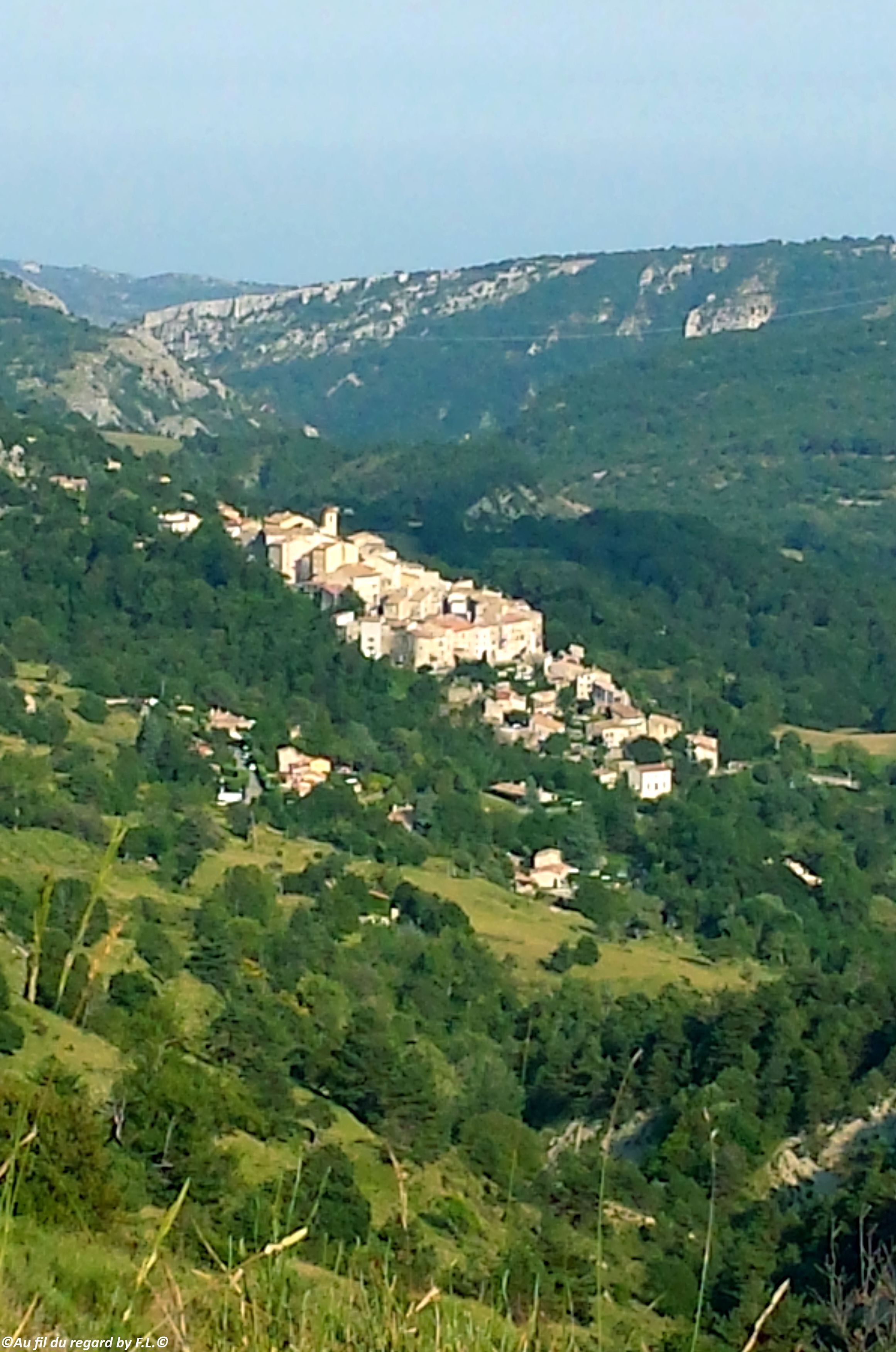 Un village perché sur une colline, avec des bâtiments traditionnels en pierre regroupés.