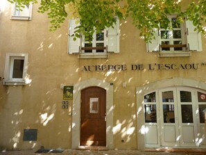 Un edificio con un letrero que dice 'AUBERGE DE L'ESCAOU' y una puerta de madera.