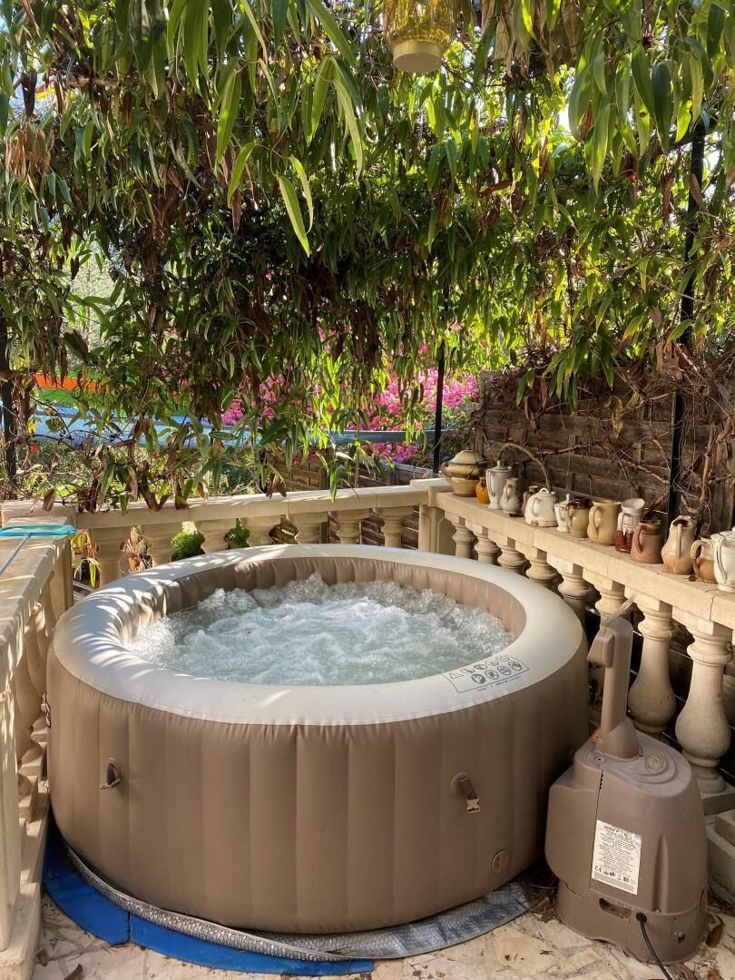 Un bain à remous entouré de balustrades en pierre, avec une pompe et un chauffe-eau situés à proximité.