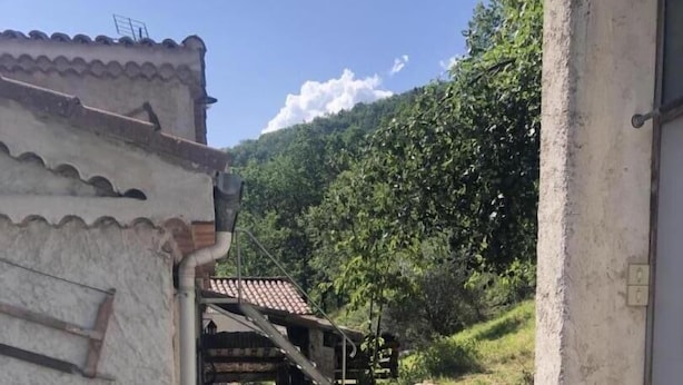 Un estrecho sendero de piedra que conduce a un edificio rústico con techo de tejas.