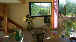Un salón acogedor con un ventanal grande, muebles de mimbre y vistas al exterior.