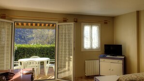 A room with a sliding glass door leading to a patio, a television, a radiator, and a small table with chairs. - Cyclamen - LA BOLLENE-VESUBIE (LA BOLLENE-VESUBIE)