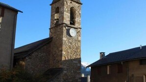 A stone tower with a clock, surrounded by buildings and a cobblestone street.
