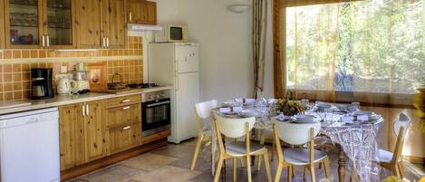 A kitchen with wooden cabinets, a refrigerator, a microwave, and a dining table set for four.
