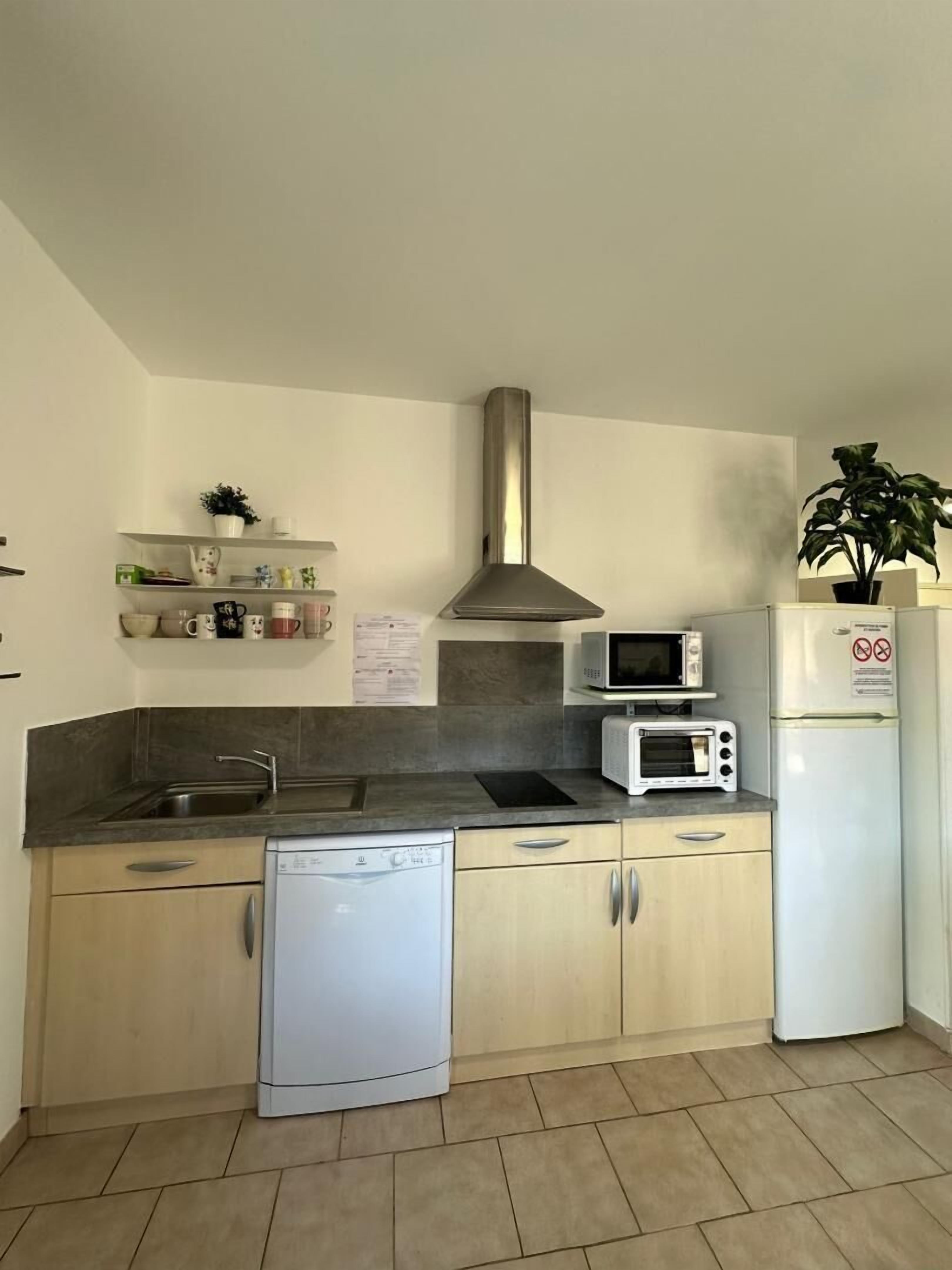Una cucina compatta con lavastoviglie, microonde, tostapane e frigorifero.