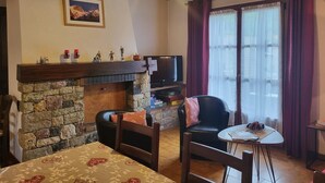 Una sala de estar acogedora con chimenea de piedra, televisor y comedor con mesa y sillas.