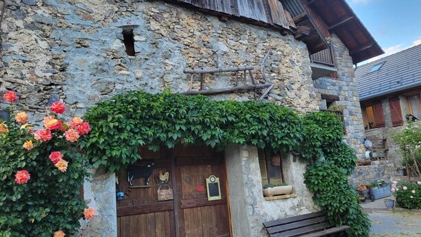 Un rústico edificio de piedra con una puerta de madera y un banco en el exterior.