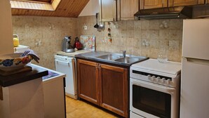 Una cocina con armarios de madera, un tragaluz, un lavamanos doble, una estufa y un lavavajillas.