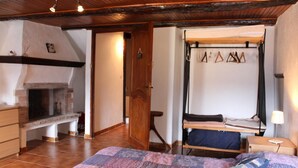 A cozy bedroom with a brick fireplace, a bed with a quilt, and a wooden door.