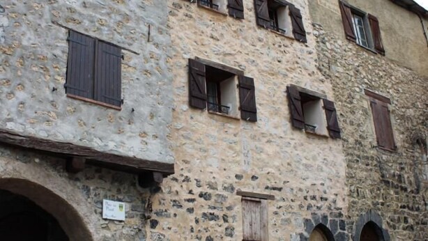 A stone building with multiple windows and a small garden area.
