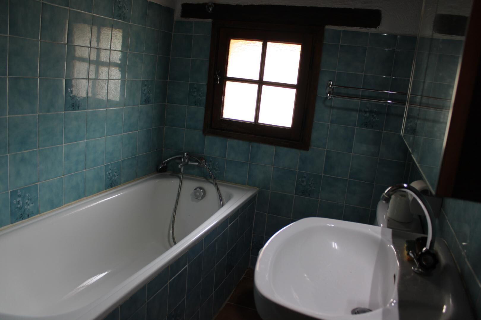 A bathroom with a bathtub, a sink, and a window.