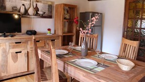 A wooden dining table set with plates, glasses, and a vase with flowers.