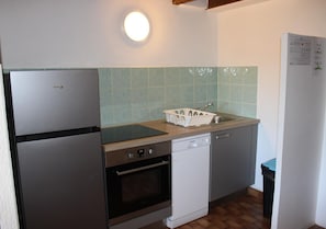 A compact kitchen with a refrigerator, oven, dishwasher, and a sink with a dish rack. - Le Génépi - ROUBION - Gîte (ROUBION)