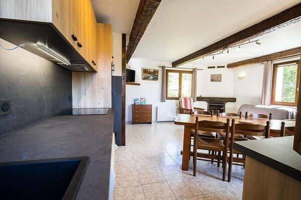 A modern kitchen with a built-in stove, wooden cabinets, and a dining area with a table and chairs.