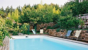 A rectangular swimming pool with a wooden deck, surrounded by stone walls and lush greenery. - L'Oustaou - La Colle-sur-Loup (La Colle-sur-Loup)