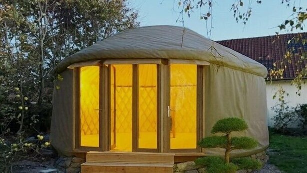 A small, covered structure with a wooden entrance and steps leading up to it, surrounded by a garden with a bonsai tree. - Hotel Les Augustines (Quend)