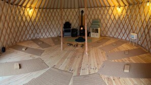 A yurt with a central fire pit, wooden flooring, and seating areas. - Hotel Les Augustines (Quend)