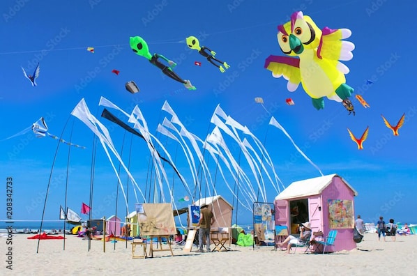 A beach with colorful kites, tents, and beach chairs.