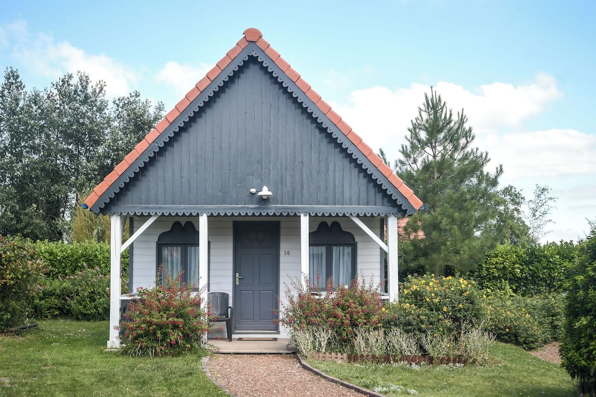 Il s’agit d’un petit bâtiment d’un seul étage, doté d’un toit gris foncé et de bordures blanches. On y trouve un porche à l’avant, avec un banc et une porte.