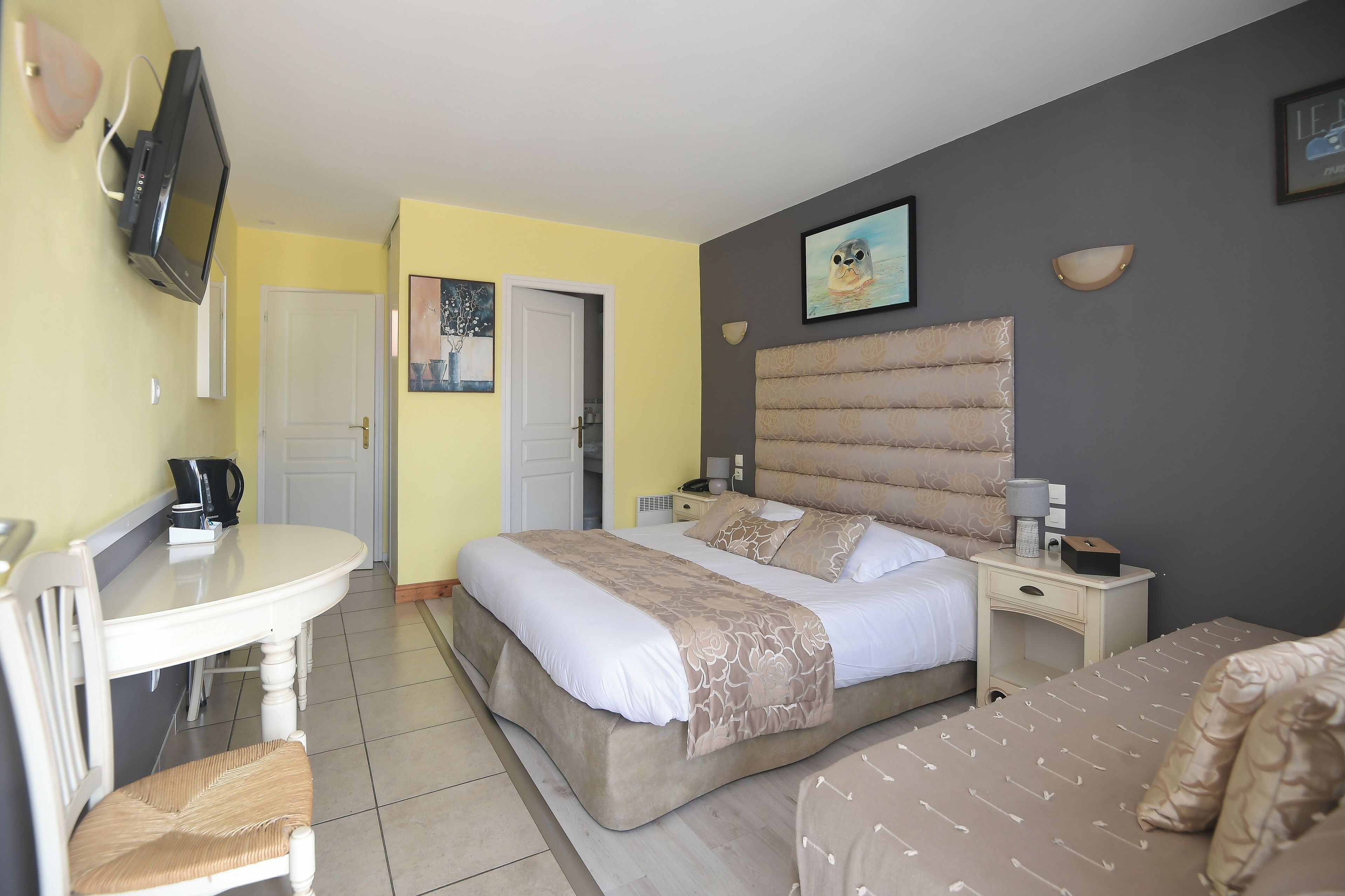 A hotel room with a bed, bedside tables, a desk, and a chair.