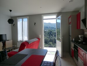 A modern kitchen with a dining area, a TV, and a balcony with a view. - Le Magnolia - Colomars (Colomars)