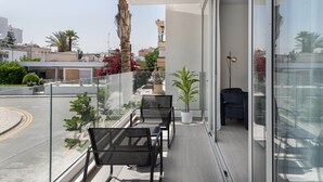 Een balkon met een plafondventilator, twee stoelen, een potplant en uitzicht op de stad.