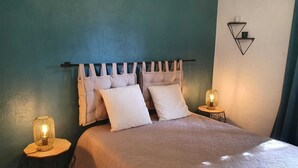 A bedroom with a bed, two bedside tables, a wall-mounted light, and a curtain.