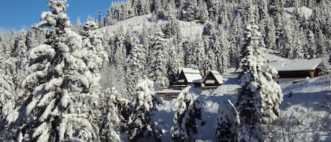Une montagne enneigée, parsemée de chalets, sous un ciel bleu azur.