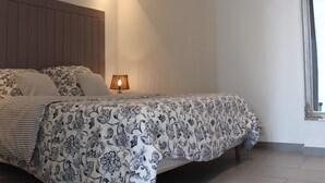 A bedroom with a bed, a bedside lamp, and a window.