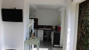 A modern kitchen with white cabinets, a red refrigerator, and a small dining area with a table and chairs.