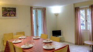 A dining area with a table set for six, a television, and curtains on the windows. - Le Balcon - PEILLE - Gîte (PEILLE)