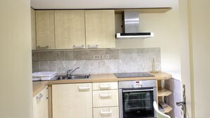 A compact kitchen with light wood cabinets, a stainless steel sink, a built-in oven, and a gas range. - Le Balcon - PEILLE - Gîte (PEILLE)