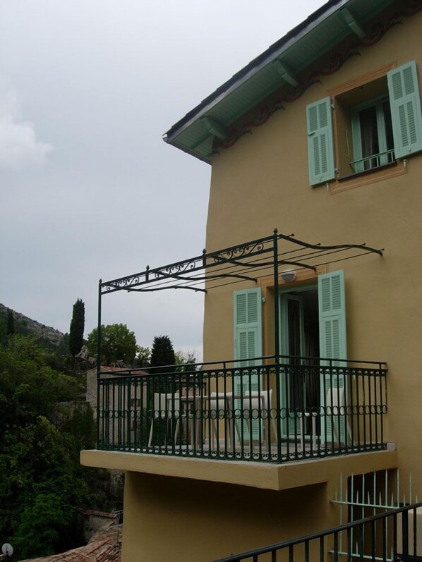 Ein zweistöckiges Gebäude mit einem Balkon und schmiedeeisernem Geländer.
