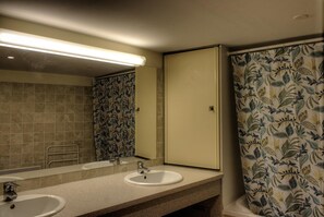 Ein Badezimmer mit zwei Waschbecken, einem Spiegel und einer blumengemusterten Duschvorhang.