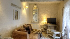 A cozy living room with a sofa, a television, and decorative wall sconces.