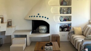 Ein Wohnzimmer mit Kamin, einer Couch, einem Couchtisch und einem Bücherregal mit Dekoration.