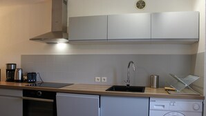Een moderne keuken met een inbouwoven, vaatwasser en wasmachine.