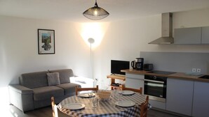 Een functionele leefruimte met een bank, eettafel en kitchenette.