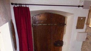 A wooden door with a metal latch, a red curtain, and a stone floor. - Bastide de la Rousoulina (LE ROURET)