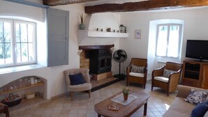 A living room with a fireplace, two armchairs, a sofa, a wooden coffee table, and a television. - Bastide de la Rousoulina (LE ROURET)