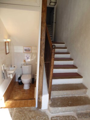 Ein Badezimmer mit Toilette, Waschbecken und einer Holztreppe, die in einen anderen Raum führt.