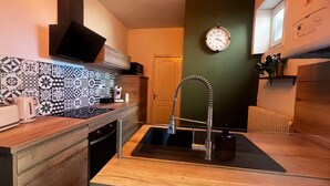Une cuisine compacte au design moderne, dotée d’un évier, d’un four à micro-ondes et d’une machine à café placés sur le plan de travail.