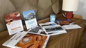 Une chambre d’hôtel bien rangée, avec des brochures, une lampe et un petit récipient sur la table de chevet.