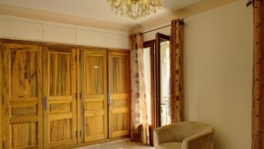 A room with a large wooden wardrobe, a beige armchair, and a chandelier. - La Maison Blanche - BLAUSASC (BLAUSASC)