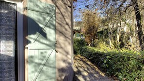 Un edificio con una puerta verde y una ventana con cortina estampada.