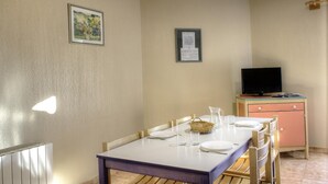 Un comedor con una mesa dispuesta para cuatro personas, un televisor en un mueble y un certificado enmarcado en la pared.