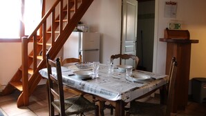A dining area with a wooden staircase, a table set with plates, glasses, and cutlery, and a refrigerator in the background.